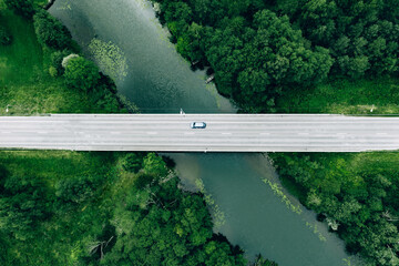 Wall Mural - Aerial view of road with blue car over the river and green woods in Finland