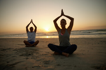 Tranquility by the ocean. a couple doing yoga on the beach at sunset.