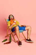 Tired Beachgoer. Man In Summer Shirt And Short With Hawaiian Flower Garland On Chest Sleeping On Sun Lounger Over Pink Background. Vacation, Summer, Rest And Male Hobbies Concept