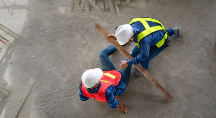 accident in site work,a piece of wood fell from height hit on a worker's legs while working at a new building, a colleague rescued him from  accident.concept risk management, safety at work