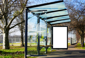 bus shelter at a busstop. blank billboard ad display. empty white lightbox sign. glass and aluminum frame structure. city transit station. bench inside. urban street setting. outdoor advertising