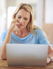 Canvas Print - Youre never alone nowadays. a mature woman using a laptop at home.