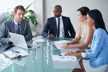 Wall Mural - Coming up with business solutions as a team. a businessman showing his colleagues something on a laptop during a meeting.