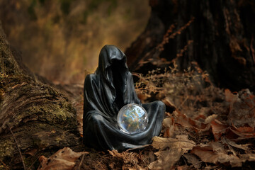 Wall Mural - Magician mysterious black cloaked figure, Grim Reaper, with crystal ball in dark forest, blurred natural background. esoteric spiritual ritual for Samhain sabbat, Halloween holiday. Wiccan witchcraft