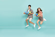 Young Asian couple in summer outfits jumping and holding water guns plastic for Songkran festival in Thailand isolated on green background