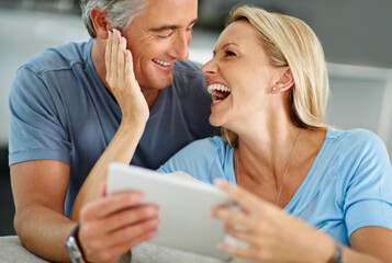 Wall Mural - Who doesnt like a good meme. a laughing couple sitting at home using a digital tablet.