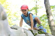baby boy climbing on a rock in the forest