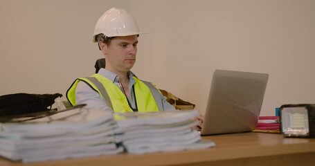 Canvas Print - Construction engineer man in the Hard Hat working sitting at table using laptop at work in workspace
