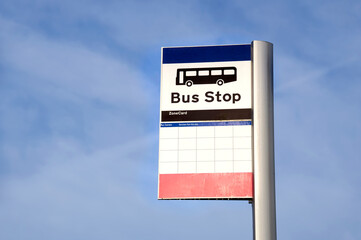 Wall Mural - Bus stop sign on post against blue sky