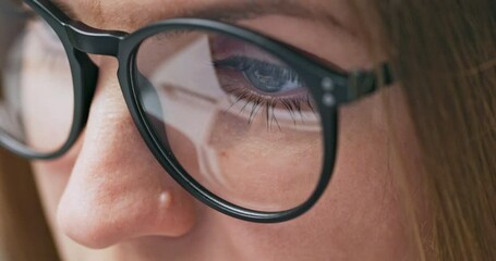 Close up view of focused woman in glasses looking at laptop screen