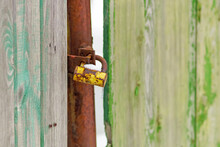 An Old Rusty Padlock Is Covered With Snow On A Wooden Fence