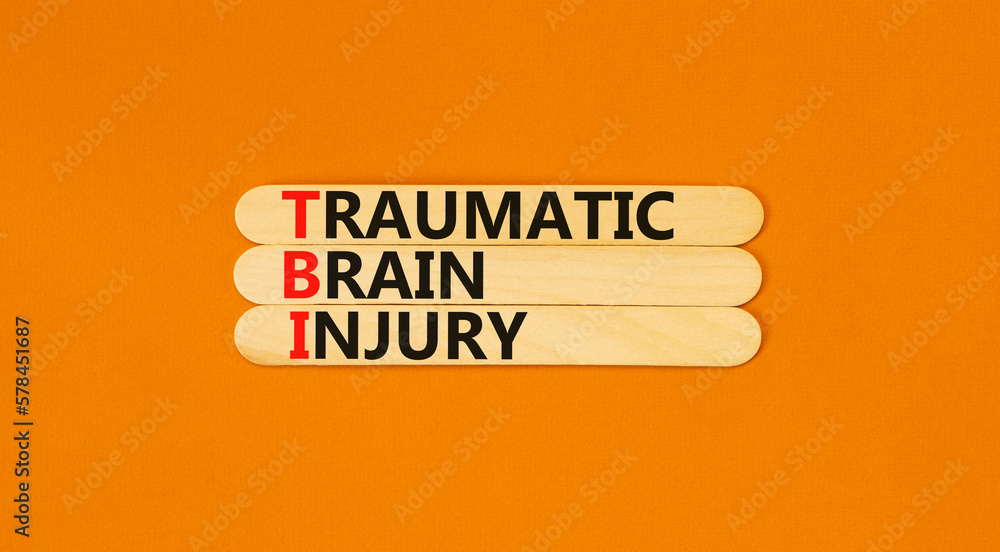 TBI traumatic brain injury symbol. Concept words TBI traumatic brain injury on wooden stick on a beautiful orange table orange background. Medical and TBI traumatic brain injury concept. Copy space.