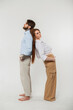 © alones - Beautiful young fashionable business couple man and woman in an elegant stylish vintage clothing with shirt and pants standing back to back on a white background