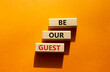 Be our guest symbol. Concept word Be our guest on wooden blocks. Beautiful orange background. Business and Be our guest concept. Copy space