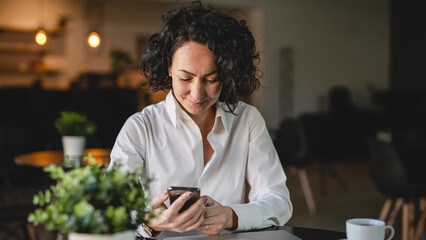 Wall Mural - One woman use smartphone mobile phone while sit at cafe or restaurant