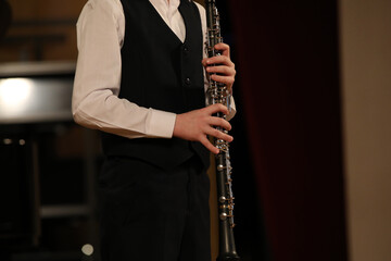 Wall Mural - A young clarinetist musician stands with a musical instrument in his hands