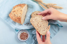 Woman's Hands Holding A Slice Of Fresh Baked Whole Grain Bread With Flax Seeds And Sesame Seeds
