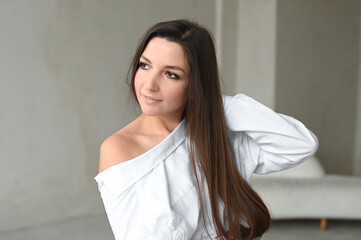 Young beautiful brunette woman in white shirt, stylish and minimalistic portrait in light colors