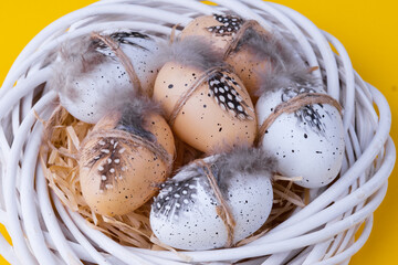 Wall Mural - Easter composition with a decorative white wreath, quail eggs in the form of a nest on a yellow