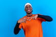 © unai - Black ethnic man in orange clothes on a blue background having fun smiling and party dancing