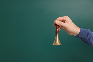 Wall Mural - Teacher with school bell near chalkboard, closeup. Space for text