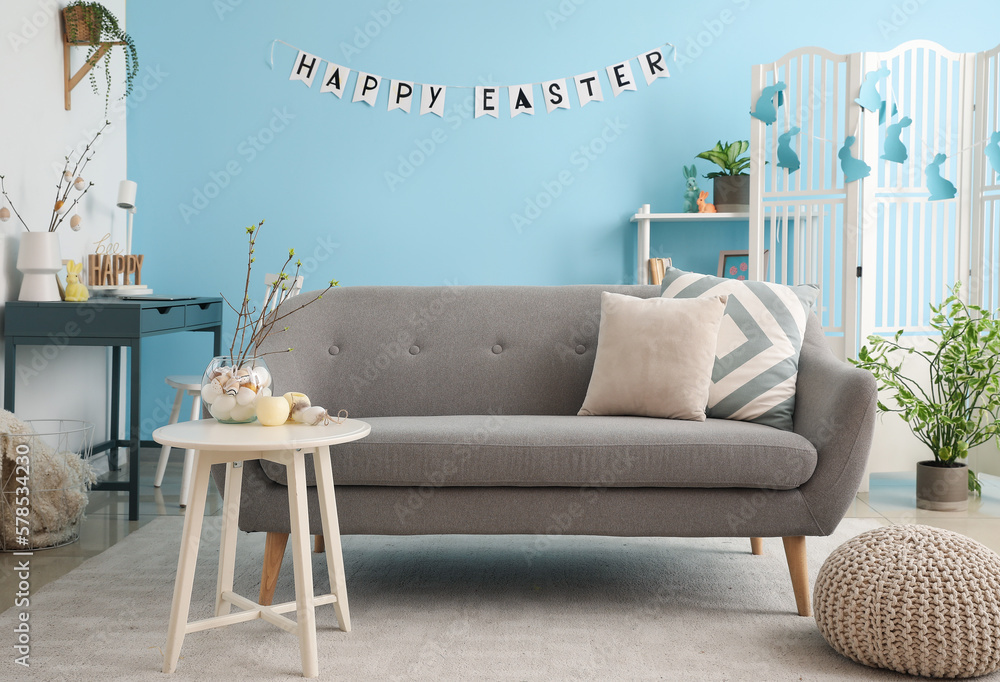 Interior of living room with sofa, workplace and Easter decor