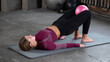An attractive woman makes a buttock bridge with a small pink pilates ball. Pilates,