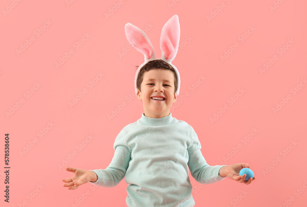 Cute little boy with bunny ears and Easter egg on pink background