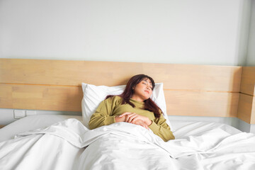 Wall Mural - Young beautiful Asian woman sleeping in her bed and relaxing in the morning