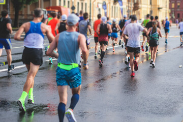 Marathon runners crowd, participants start running the half-marathon in the city streets, crowd of joggers in motion, group athletes outdoor training competition in the rain