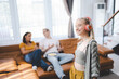 © chokniti - Happy young girl uses headphones to listen to music while relaxing at home with her family, and a gorgeous smiley woman enjoys her pastime and leisure time in the entertainment room.