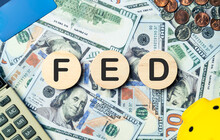 FED Text In Wooden Circle On Banknotes Background, Credit Card, Piggybank, Calculator. Federal Reserve Board System Federal Reserve Interest Rate Hike, Global Economy, Recession And Finance Concept.