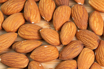 Almond nuts on wooden background close up. Product rich in minerals and vitamins. Almond kernels. Healthy skin and hair and natural healing oil treatment