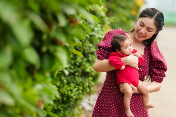 Wall Mural - mother holding and playing with baby newborn in the garden