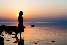 Silhouette Woman Standing On The Rock At Sea Shore