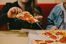 Cropped Image Of Woman Holding Pizza Slice At Restaurant