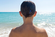 Rear View Of Young Boy Looking To The Sea In A Sunny Day