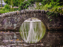 Fountain Reflected On Pond Under Footbridge In Queenstown, New Zealand