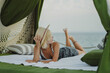 © Cavan Images - Woman in a pavilion on the seashore, vacation.