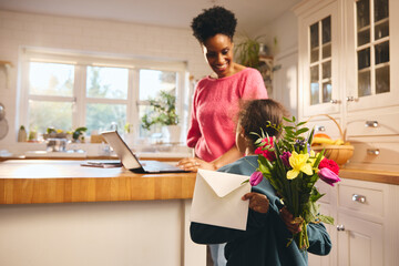 Boy giving mother bouquet and Mother's Day or Birthday card