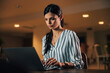 © bnenin - Focused female woman typing on a laptop, sitting at the office.