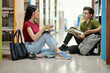 © DragonImages - Positive classmates discussing homework in school library