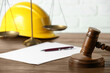 © New Africa - Labour, construction and land law concepts. Judge gavel, scales of justice, protective helmet, paper sheet with pen on wooden table