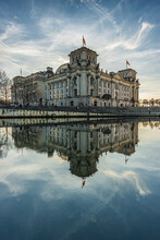 Reichstag In Berlin. German Government Building In The Center Of The Capital. Spree In The Foreground With Reflection Of The Building In The Sunshine. Clouds In The Sky For The Winter Month