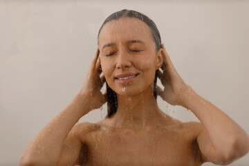 Wall Mural - Young woman under trickles water in pleasure shower. Beautiful girl under spray of water on isolated background. Wet happy face