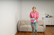 Full-size picture of happy smiling girl doing house cleaning. Washing floors. Cute young woman in casual clothes and rubber gloves wipes the floor with mop in the living room.