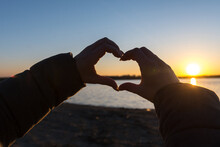 A Heart Made Of Hands On The Background Of The Setting Sun Near The River
