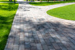 © LariBat - Paving with paving slabs. Landscape architecture of a park. Decorative garden winding pathway walkway and a green lawn with ornamental bushes