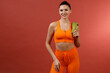 Young positive smiling woman in orange fitness sport outfit cloth with towel studio isolated shot.