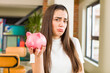 © kues1 - pretty young woman with a piggy bank. savings concept. house interior design